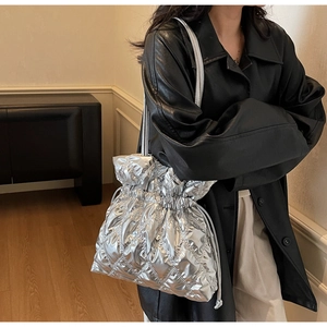 Close-up of silver quilted tote bag with drawstring closure and metallic finish