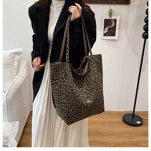 Close-up of leopard print canvas tote bag with brown handles and metal brand tag