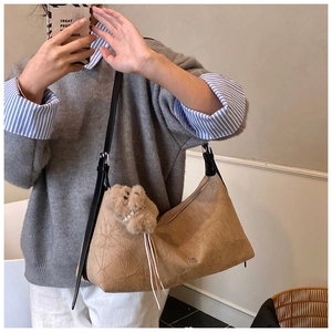 Detail of khaki crinkled texture underarm bag with a cute plush bear pendant accessory