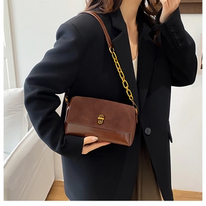Détail du sac en daim marron et cuir avec fermoir rotatif doré et chaîne dorée