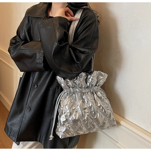 Detail view of quilted silver metallic drawstring bag styled with a black leather jacket