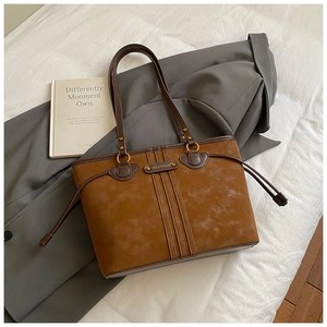 Détail du sac cabas en daim marron avec cordons de serrage sur fond de tissu gris chic
