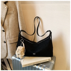 Detail of black wrinkled nylon tote bag with white logo and brown plush bear charm