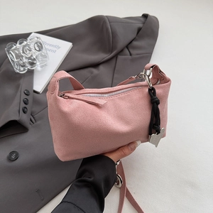Detail of pink suede handbag featuring silver heart pendant and woven knot accessory
