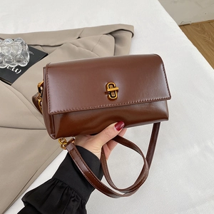 Détail d'un sac bandoulière en cuir marron avec fermoir doré et esthétique vintage