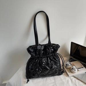 Detail of glossy black quilted tote bag with drawstring closure and chic lattice texture