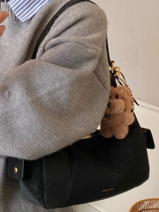 Chic black faux suede shoulder bag with gold hardware and brown dog plush charm pendant