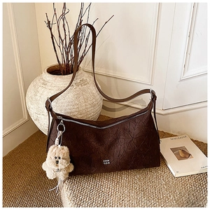 Detail of vintage brown tote bag with pleated texture and plush bear charm