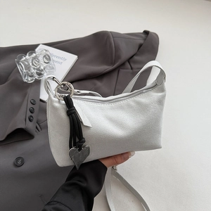 Detail of grey suede shoulder bag featuring a silver metal ring and black heart pendant