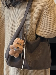 Sac fourre-tout en daim marron avec breloque chiot porté sur un pull beige pour femme