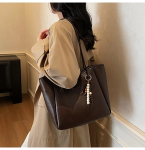 Detail of coffee brown tote bag with beaded tassel and polished faux leather texture