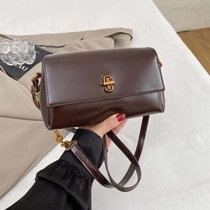 Détail du sac à main en cuir marron foncé avec fermoir doré et bandoulière en chaîne