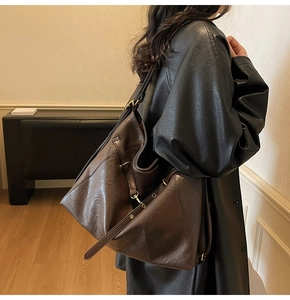 Détail d'un sac cabas en cuir vintage marron foncé avec anneau métallique et boucle