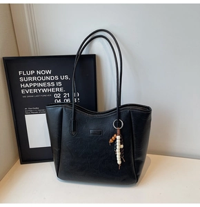 Detailed macro shot of a black vintage faux leather tote bag with beaded pendant