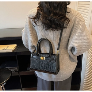 Model view of black crocodile pattern crossbody bag with golden metal hardware detail
