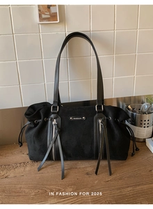 Detail of black suede tote bag featuring metallic MUONSHARK logo and zipper tassels