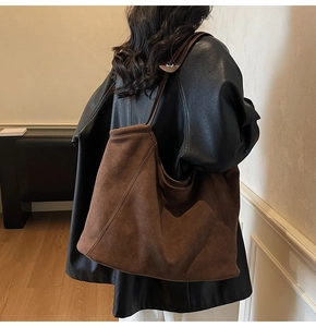 Detail of a large dark brown suede tote bag showing soft texture and natural drape
