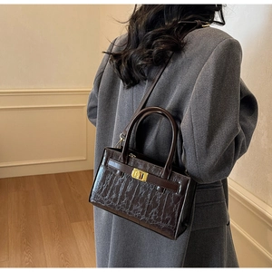 Close-up of deep brown crocodile pattern texture and golden rotating lock on the crossbody bag