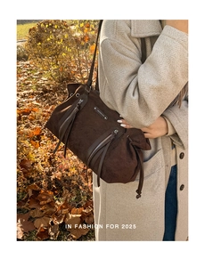 Detail of a dark brown suede hobo bag with dual vertical zippers and a soft texture