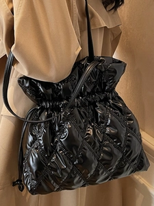 Chic black quilted drawstring handbag with glossy finish and slim shoulder strap