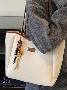 Large beige tote bag with dark brown straps and fringe tassel, stylish shoulder bag