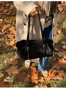 Close-up of black suede tote bag featuring dual vertical zippers and silver metal logo