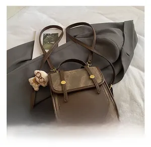 Détail d'un sac à main vintage en cuir marron avec boucle en métal et pendentif ours