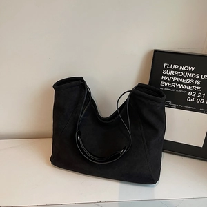 Detailed view of large black suede tote bag placed on a white marble surface