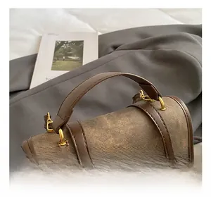 Détail d'un sac à dos vintage bicolore avec poignée en cuir et pompon décoratif blanc