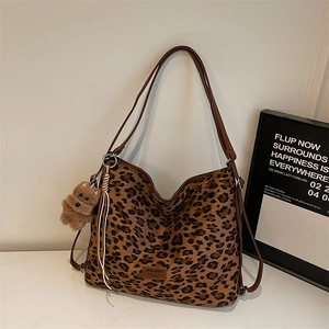 Détail d'un sac cabas à imprimé léopard avec doubles anses et breloque ours en peluche