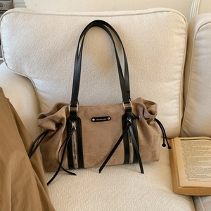 Detailed view of brown suede tote bag with black leather straps and silver zippers