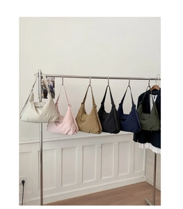 Six colors of nylon hobo shoulder bags hanging on a rack in a minimalist interior