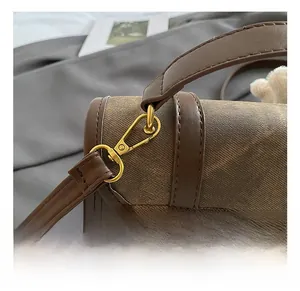 Détail du crochet en métal doré et des coutures en cuir marron sur le sac à dos
