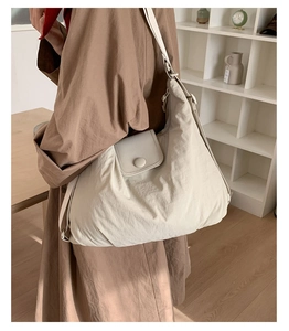 Detail of large beige nylon tote bag with front pocket and adjustable strap