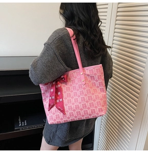 Detail view of pink tote bag featuring traditional red pattern and silk bow decoration