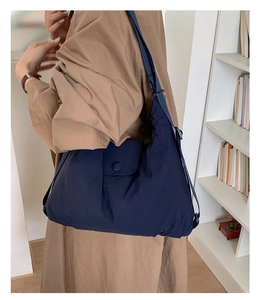 Detail view of navy blue tote bag with adjustable wide shoulder strap on model in cozy room