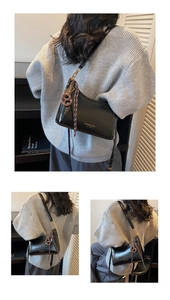 Dettaglio borsa a spalla in pelle lucida nera con logo dorato e ciondolo intrecciato