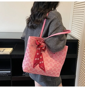 Detail of pink canvas tote bag with red Xi pattern and velvet bow ribbon on strap