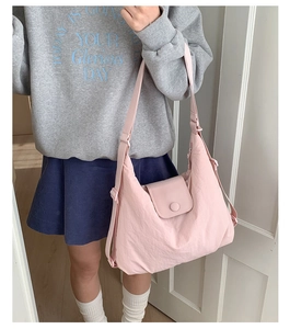 Detailed shot of large light pink nylon tote bag worn by model in casual style