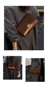 Détail du sac bandoulière en daim marron foncé avec boucle dorée sur feuilles d'automne
