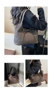 Detail of dark brown suede tote bag featuring a decorative bow and embossed brand text