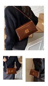 Détail du sac en cuir marron brillant montrant la boucle carrée dorée et la chaîne