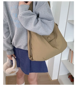 Lifestyle shot of khaki large capacity nylon tote bag worn on a model's shoulder