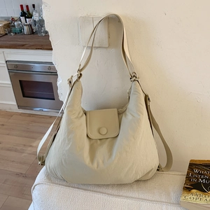 Close-up of beige hobo tote bag with flap snap button closure and textured fabric