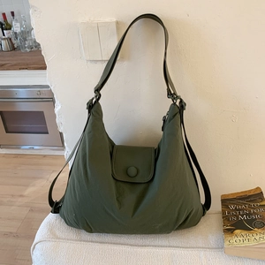 Detail of dark green tote bag showing wrinkled nylon texture and front flap buckle