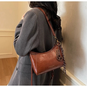Vista dettagliata della trama in pelle marrone vintage e della zip in bronzo sulla borsa a tracolla