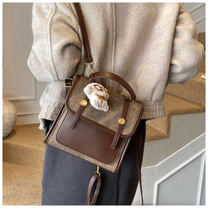 Détail du sac à dos en daim color-block avec un petit pendentif ours en peluche blanc
