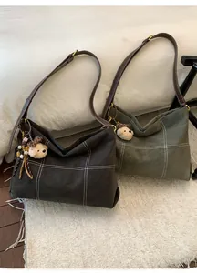 Detail of dark coffee and moss green tote bags with contrast stitching and bear charms