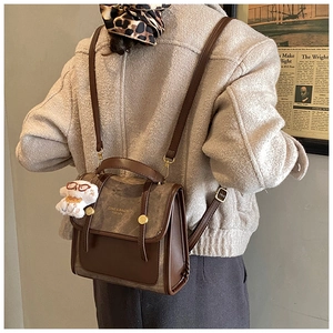 Détail d'un sac à dos en daim bicolore avec sangles en cuir et pendentif ours en peluche