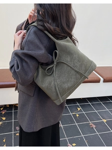 Detailansicht der olivgrünen Wildleder-Schultertasche mit Schleife und Logoprägung